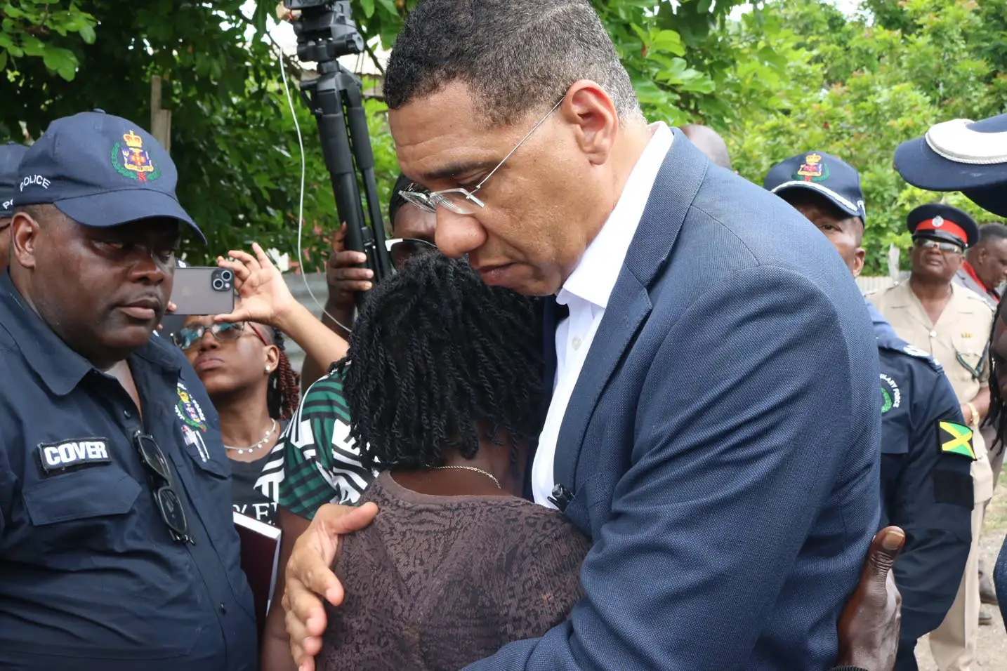 Prime Minister Andrew Holness on Monday consoles Debbie-Ann Hamilton Francis who lost her husband, daughter, and cousin to the hands of gunmen in Cherry Tree Lane, Clarendon, on Sunday.Photos: Llewellyn Wynter