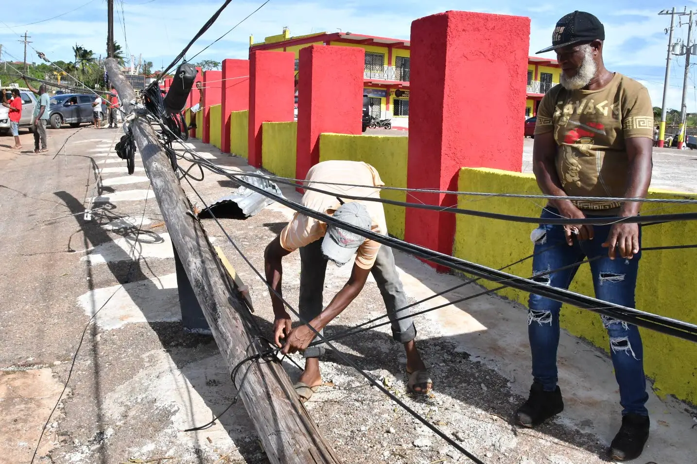 Humley Honeyghan (right) and Andy Stephenson secure utility wires on this pole last Friday at Pedro Cross in south-western St Elizabeth. The utility pole is among many that fell during the passage of Hurricane Berylon July 3, 2024.Photo: Karl Mclarty