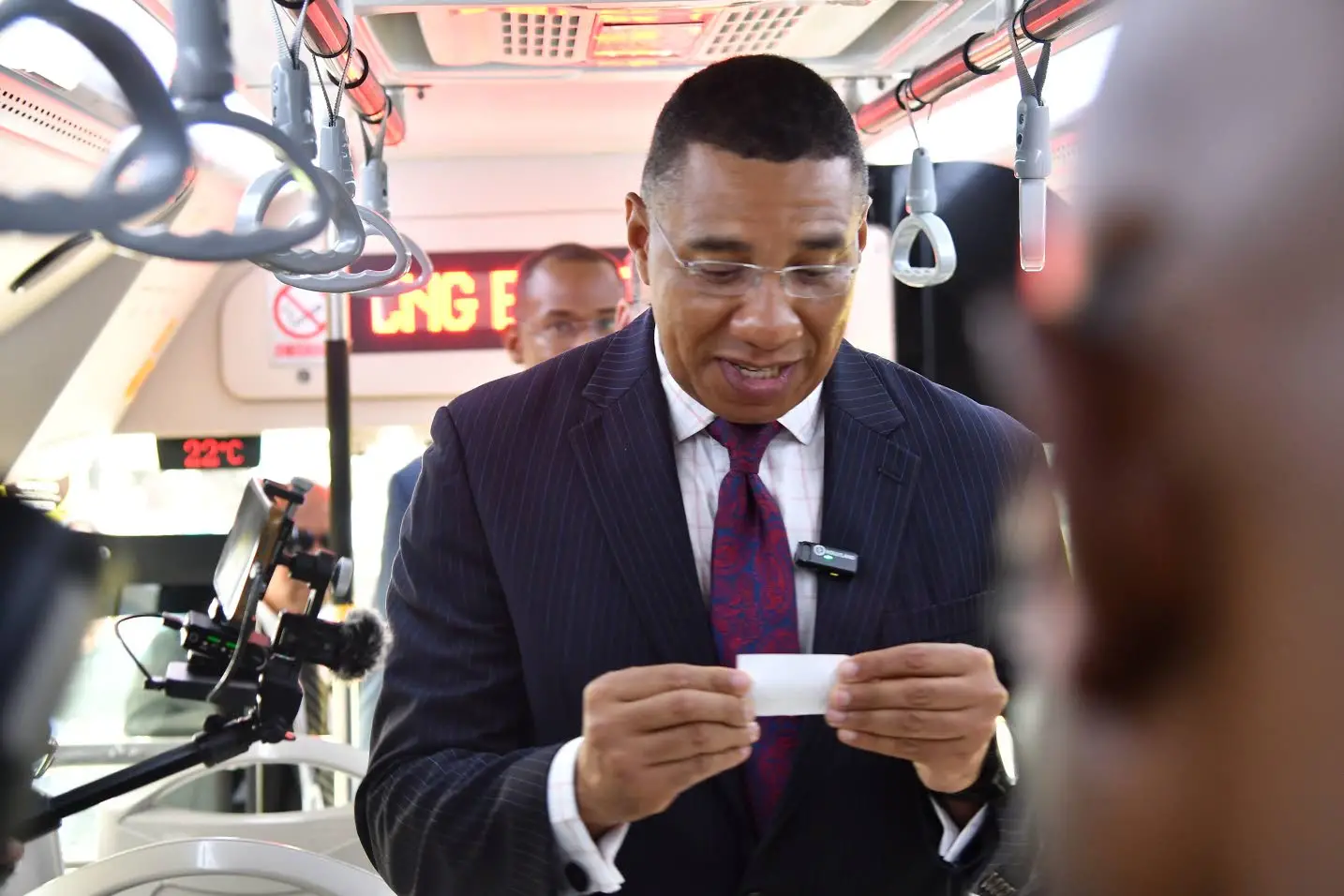 Prime Minister Andrew Holness examines one of the new Jamaica Urban Transit Company cards during the handover of 100 new buses to the State-owned company on Tuesday.