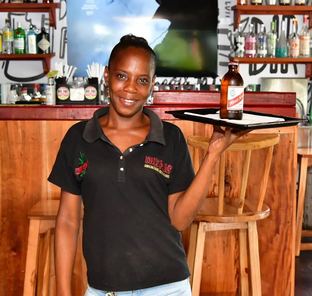 Kayann Hunter, server, delivers a Red Stripe beer from the bar.Aceion Cunningham