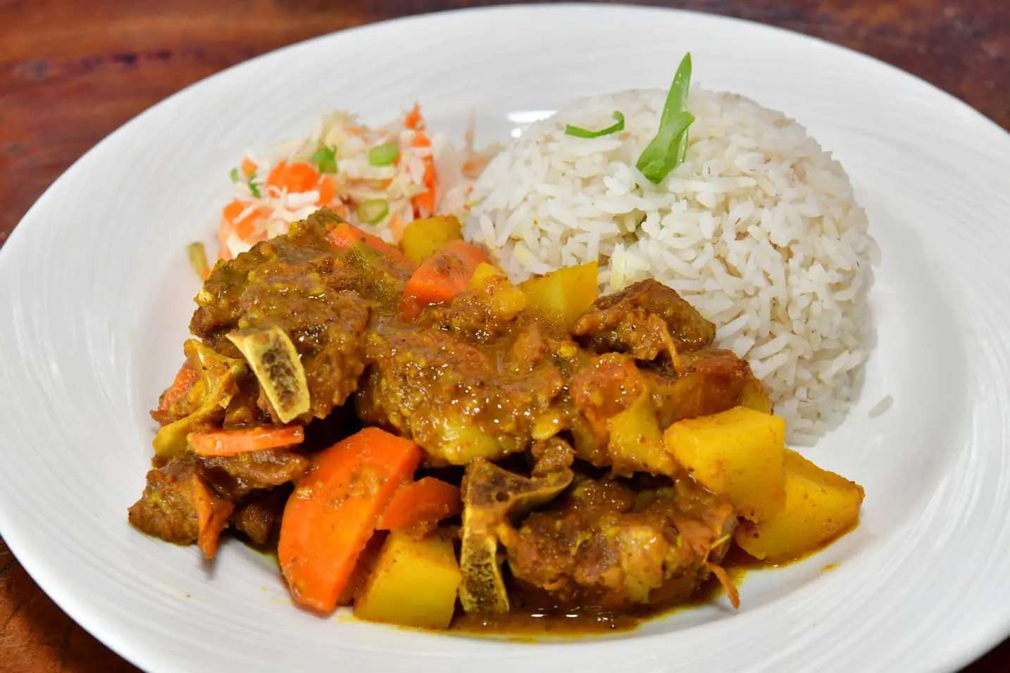 Curried goat with a side of rice and vegetablesAceion Cunningham